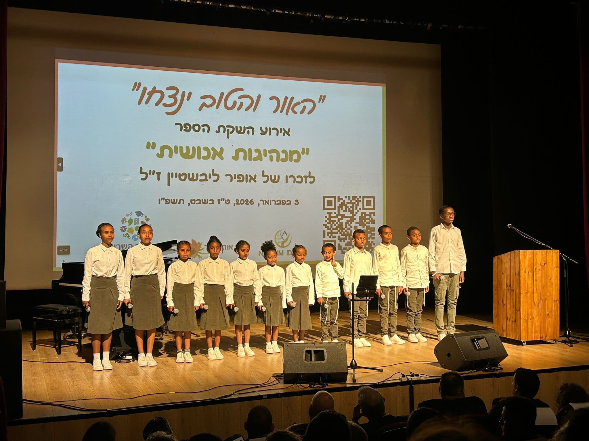 גבר ושני ילדים עם מחברת כתומה באירוע קהילתי